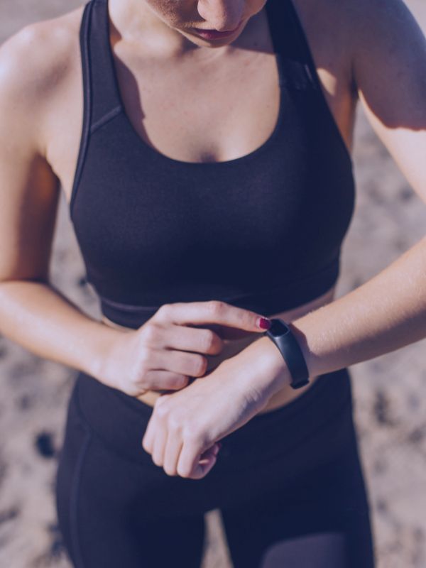 Mujer bajo el sol con pulsera medidora de rayos solares